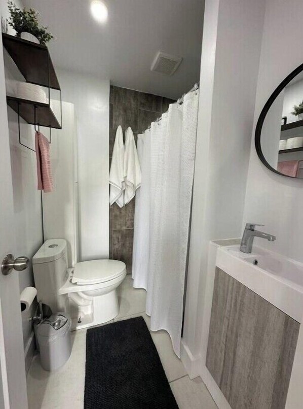 A modern bathroom with a toilet, sink, and shower curtain.