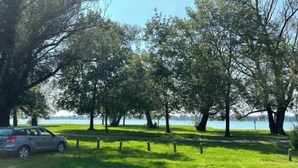 Un parc avec une voiture garée sur le côté, des arbres et une étendue d’eau en arrière-plan.
