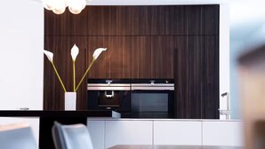 A modern kitchen with dark wood cabinetry, a stainless steel range hood, and a built-in oven.