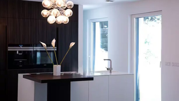 A modern kitchen with a central island, built-in appliances, and a large window.