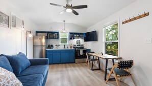 A compact kitchen with blue cabinets, a stainless steel refrigerator, and a dining area with a wooden table and chairs. - Welcome to Casa Antigua – Your Perfect Getaway in San Marcos (San Marcos)