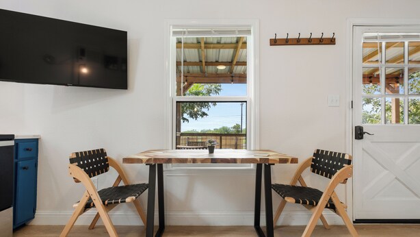 A room with a wooden table and two chairs, a TV mounted on the wall, and a window with a view of the outdoors. - Welcome to Casa Antigua – Your Perfect Getaway in San Marcos (San Marcos)