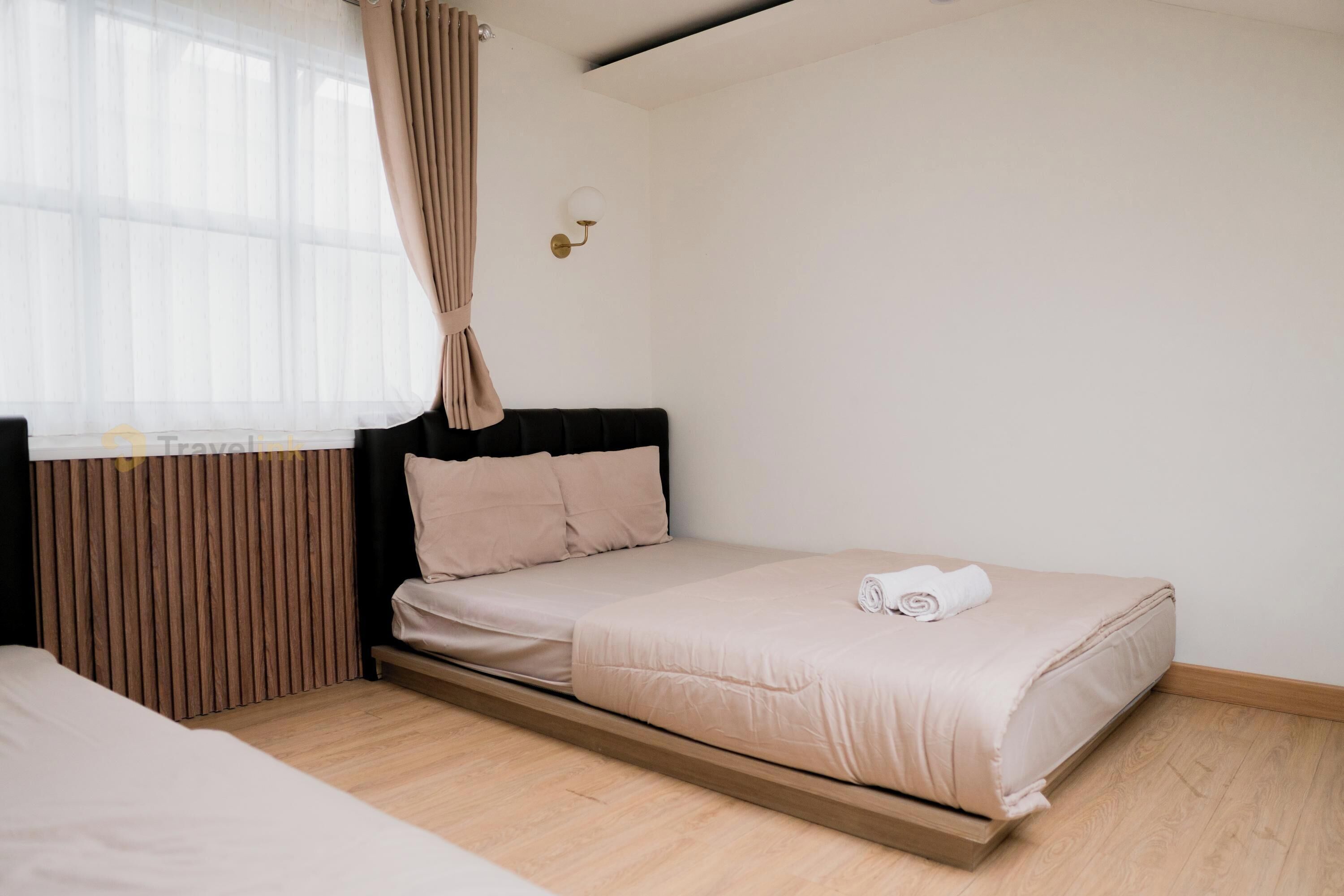 A modern bedroom with a bed, a nightstand, a wall-mounted lamp, and a window with curtains.