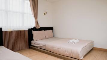 A modern bedroom with a bed, a nightstand, a wall-mounted lamp, and a window with curtains.