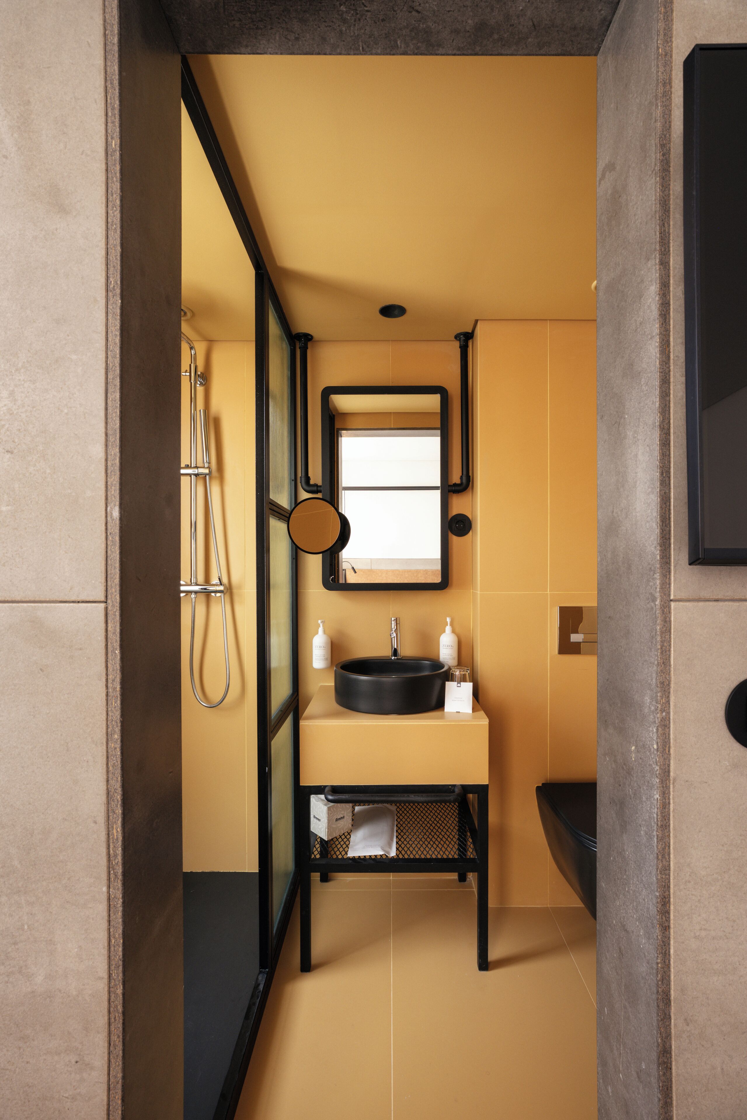 Un baño pequeño con lavabo negro, espejo y ducha.