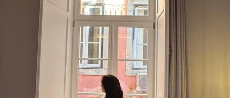 Una persona vestida con una bata blanca de pie al final de una escalera estrecha, con vista a un edificio.