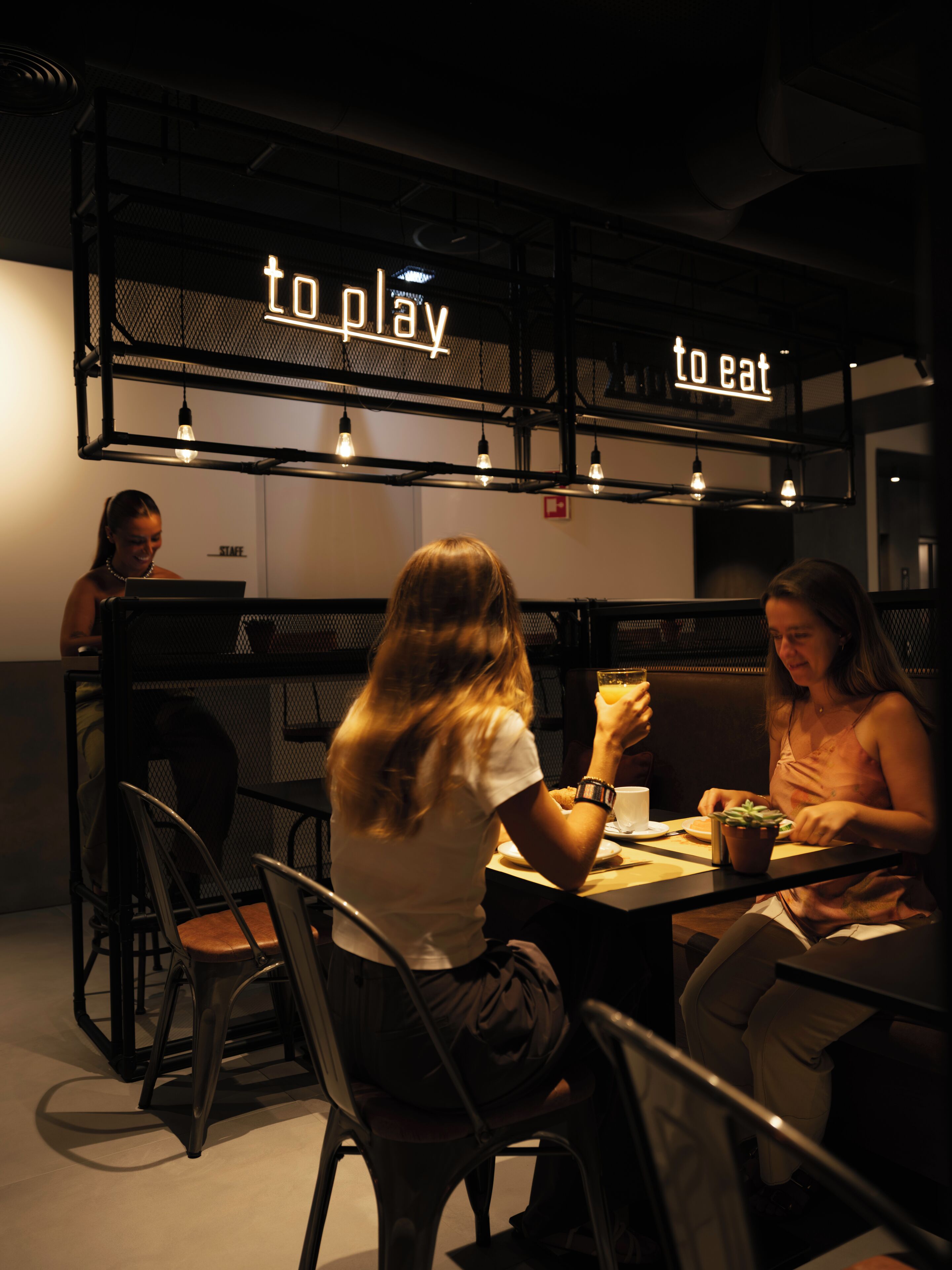 Un espace repas moderne avec un panneau indiquant « endroit pour jouer », des tables, des chaises et un panneau indiquant « endroit pour manger ».