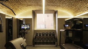 Ein Fitnessraum mit Laufbändern, einem Wandfernseher und einer Dumbbell-Halterung.