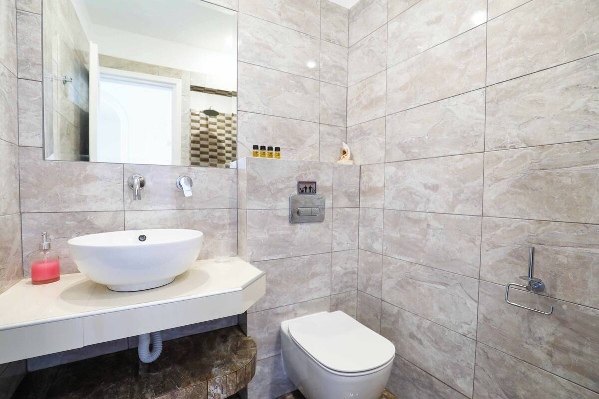 A bathroom with a white sink, mirror, and toilet.