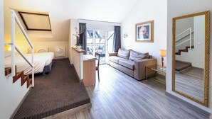 Una camera d'albergo con un letto, una scrivania, un divano, uno specchio e una scala.