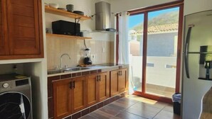 Eine Küche mit Holzausstattung, einer integrierten Waschmaschine und einer Schiebetür zu einem Balkon.