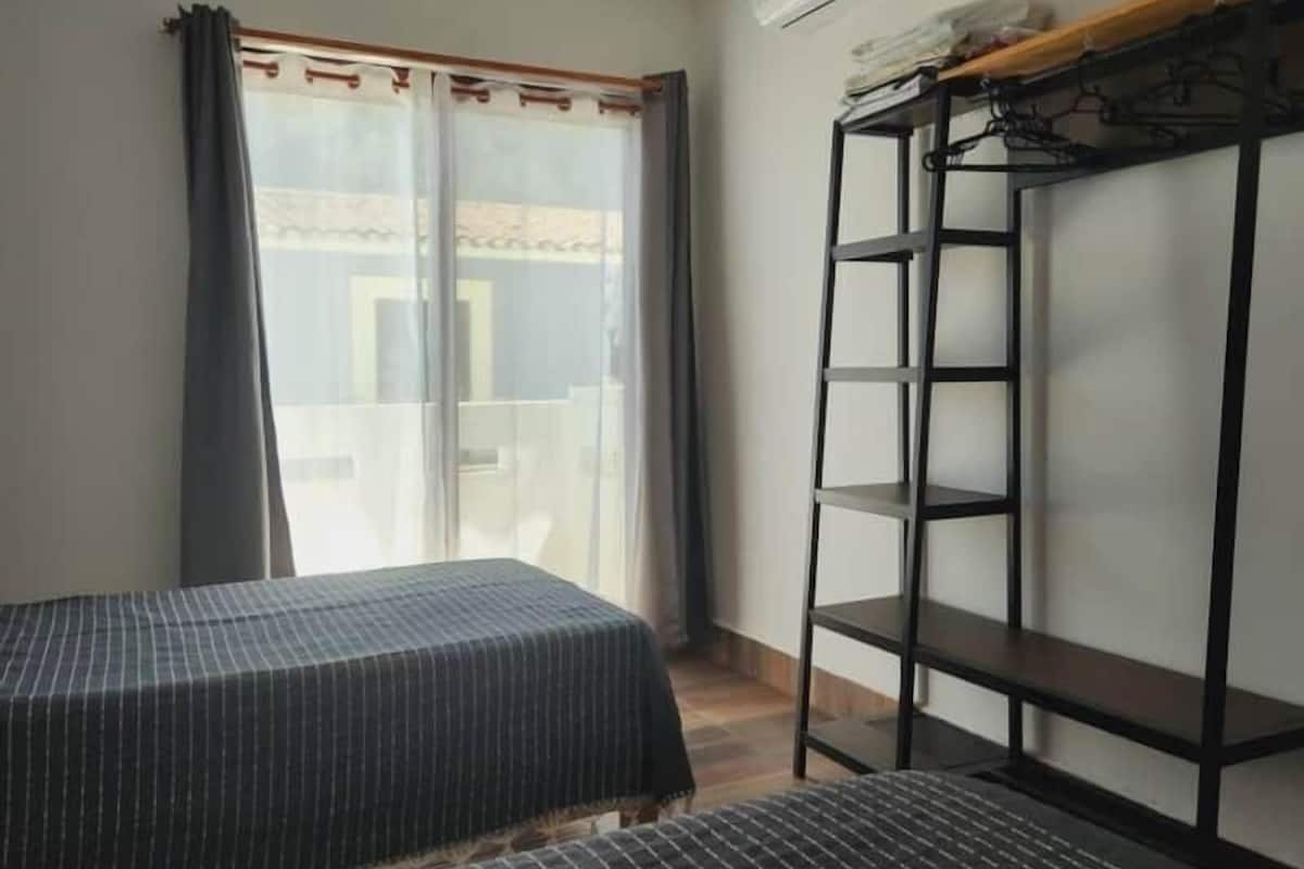 A room with a bed, a small table, a wardrobe, and a window with curtains.