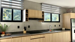 Una cocina moderna con armarios de madera, un refrigerador de acero inoxidable y una ventana con vistas a la vegetación.