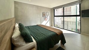 Un dormitorio con cama, ventana y aire acondicionado instalado en la pared.