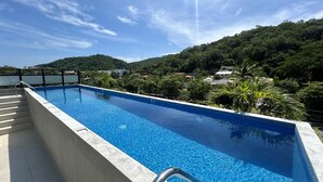 Una piscina rectangular con agua azul cristalina, rodeada por una plataforma de concreto y barandales de metal.