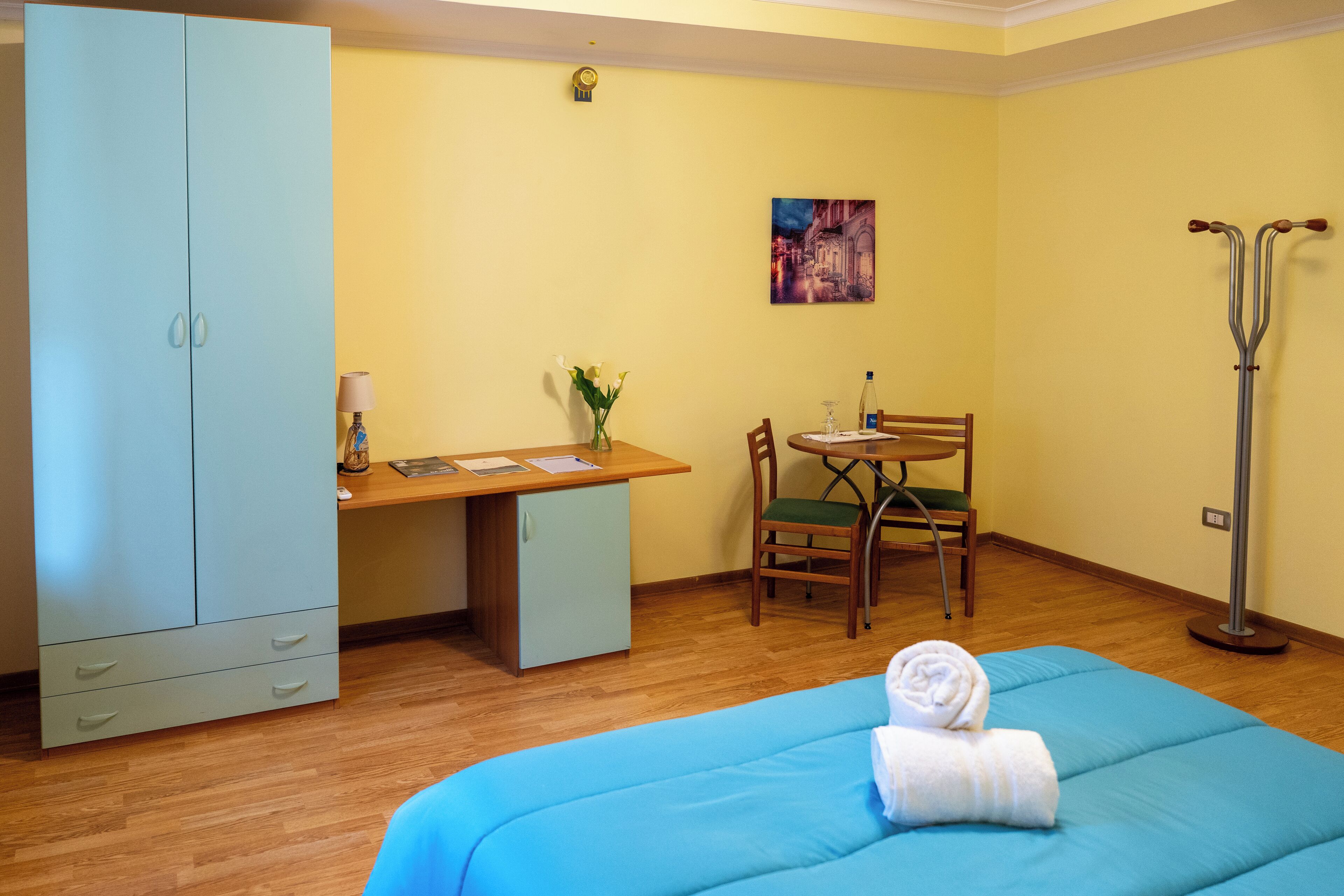 Une pièce comprenant un lit, un bureau, une chaise, une armoire et une béquille.