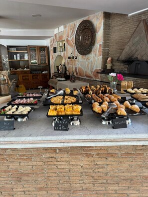 Un buffet proposant une variété de pâtisseries et un mur en pierre agrémenté d’une assiette décorative.