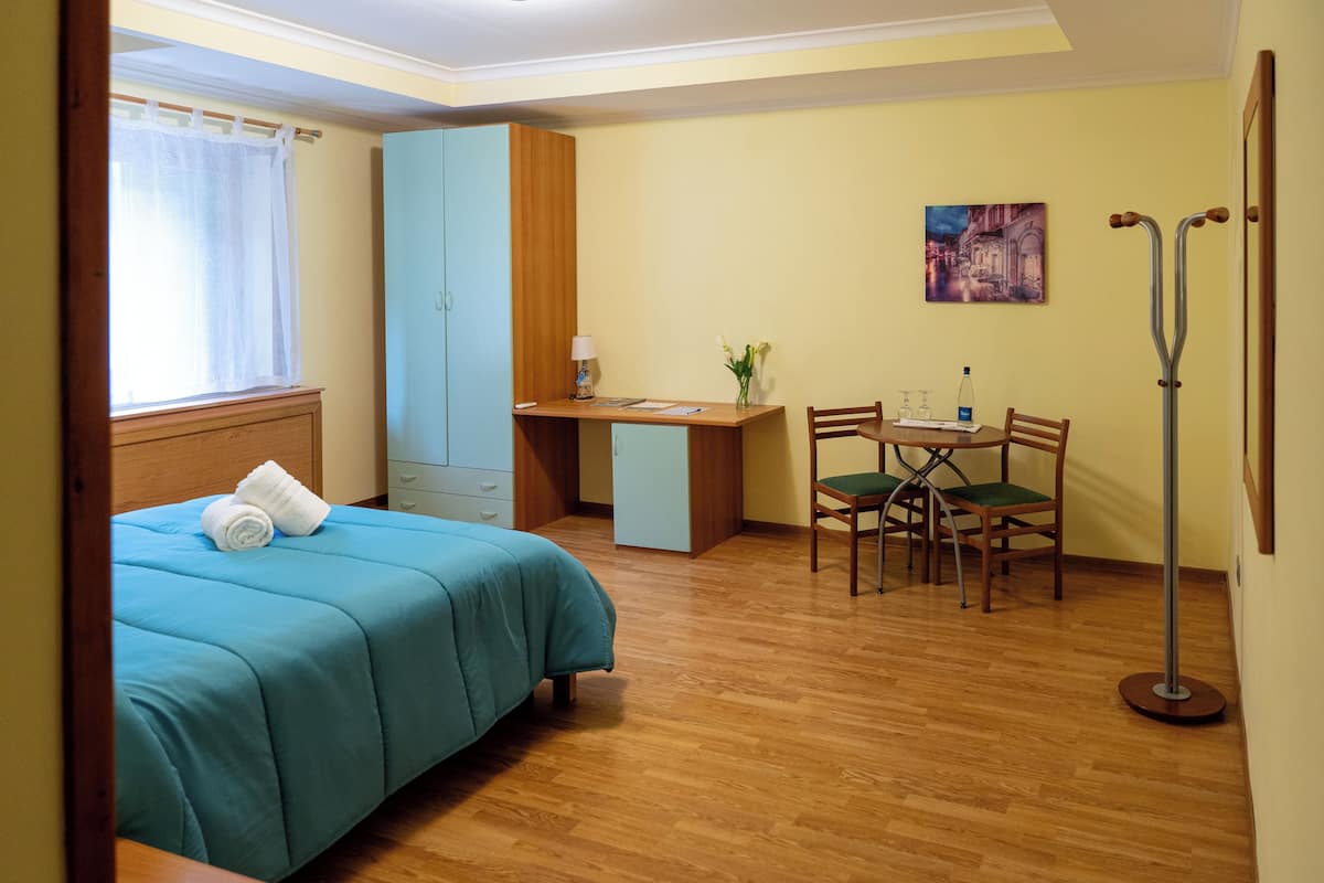 A bedroom with a bed, a desk, and a chair.