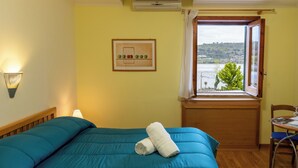Ein Schlafzimmer mit Bett, Fenster mit Blick, Stuhl und Wandlampe.