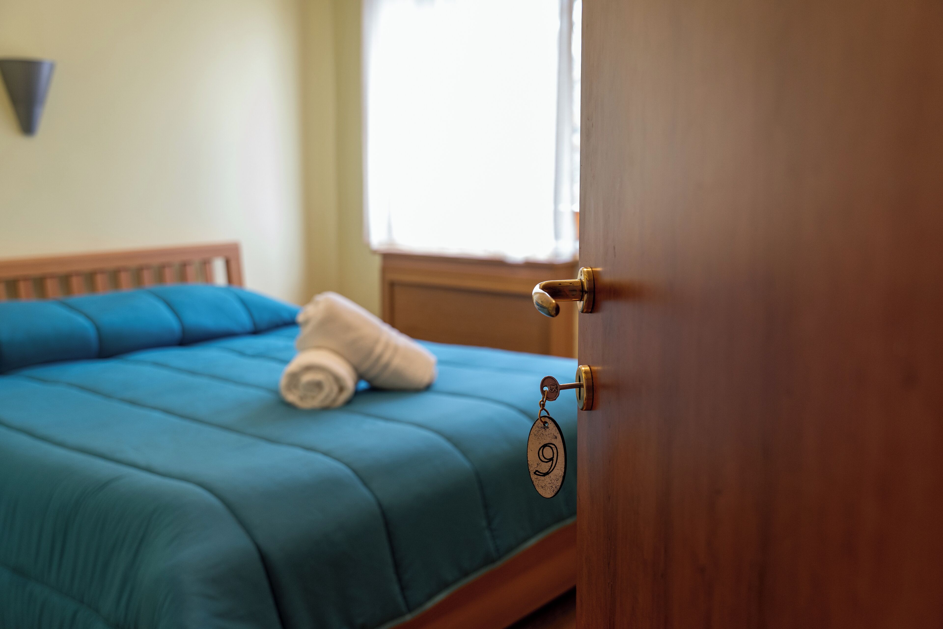 A room with a bed, a wooden door, and a window.