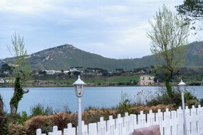 Une vue sur le lac, avec une clôture blanche en bois, des lampadaires et une colline où se trouvent des bâtiments en arrière-plan.