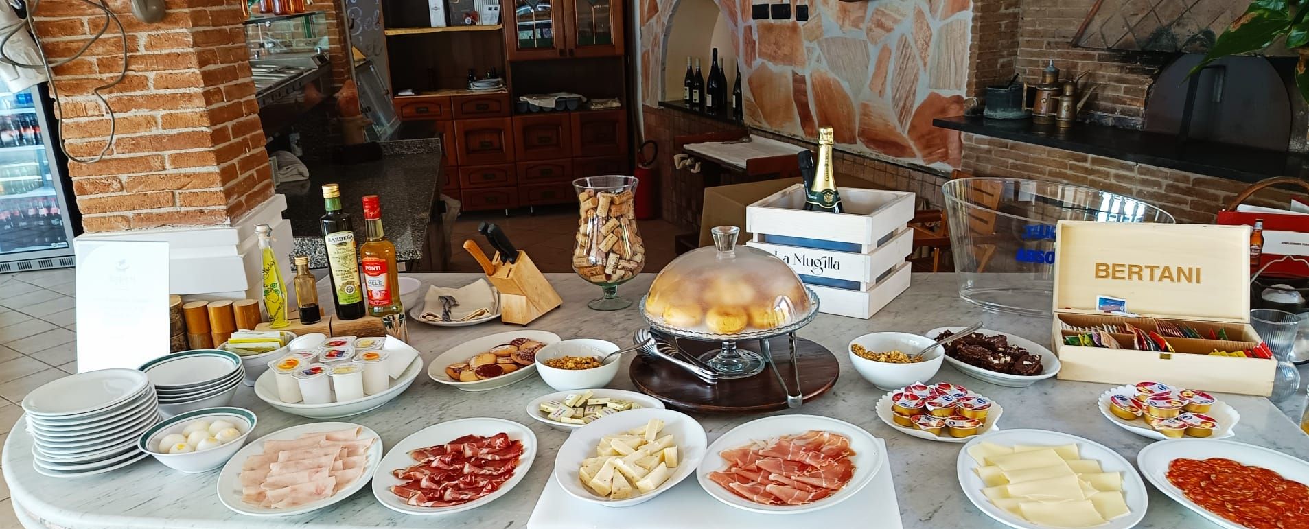 Una mesa de buffet con diversos alimentos, incluyendo carnes, quesos y una estación de queso fundido.