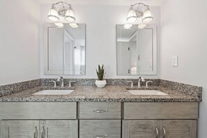 A bathroom with two sinks, a potted plant, and a mirror above each sink.