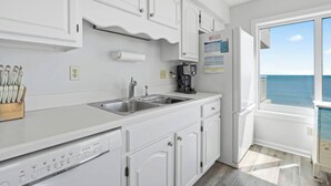 A kitchen with white cabinetry, a stainless steel sink, and a Bosch dishwasher. - Corner, Oceanfront Balcony- Pool- Upscale Design (North Myrtle Beach)