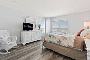 A bedroom with a bed, a dresser, a television, and a rocking chair.