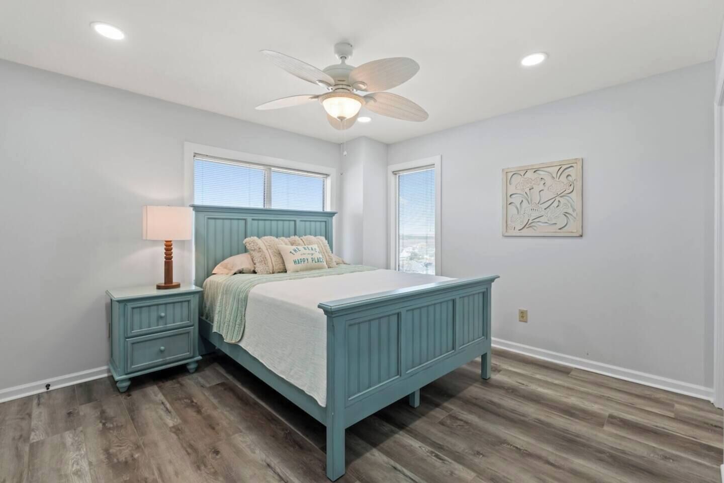 A bedroom with a bed, nightstands, a ceiling fan, and a window.