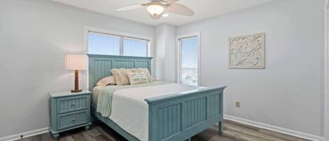 A bedroom with a bed, nightstands, a ceiling fan, and a window.