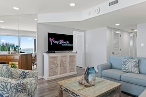 A modern living room with a television, a sofa, and a coffee table. - Corner, Oceanfront Balcony- Pool- Upscale Design (North Myrtle Beach)