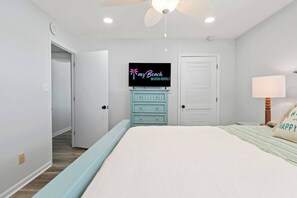 Un dormitorio con una cama, un televisor en la pared, un aparador y una puerta.