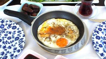 A table with various dishes including a pan with eggs, bowls of olives, and a plate of fresh vegetables.
