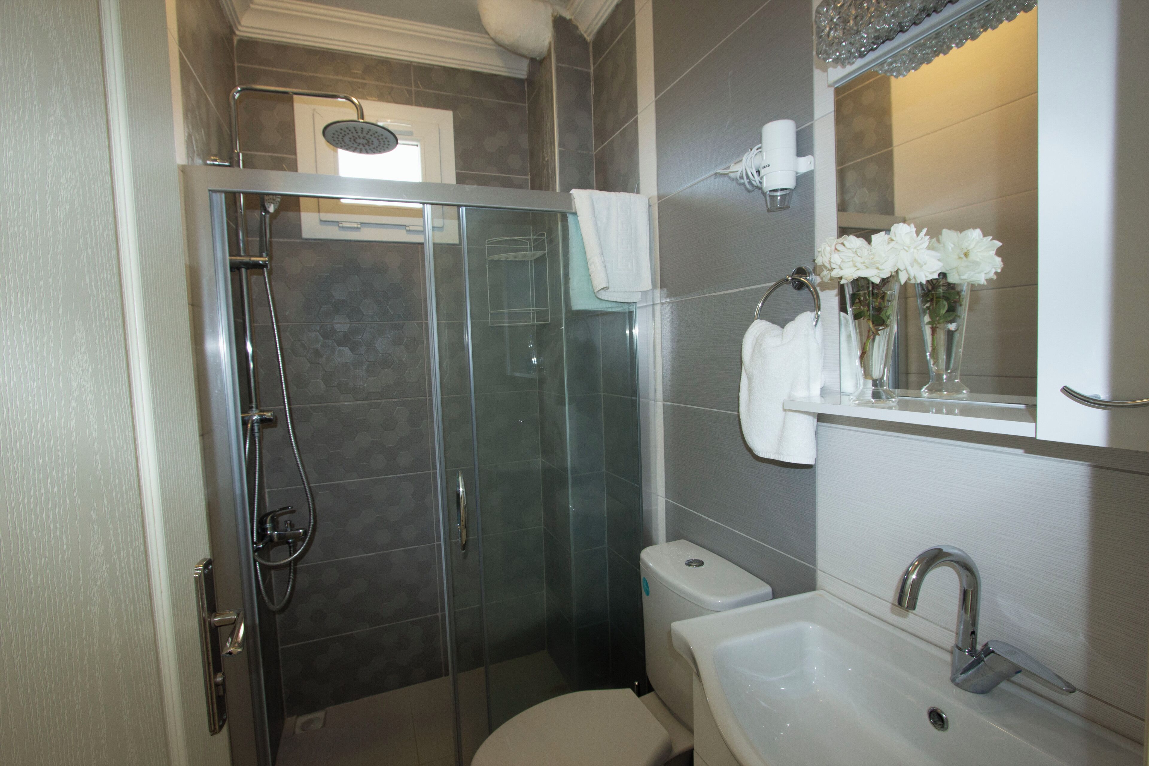 Un baño moderno con ducha de vidrio, inodoro y lavamanos con espejo.