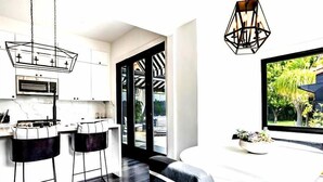 A modern kitchen with white cabinets, a built-in oven, and a large window overlooking a garden.