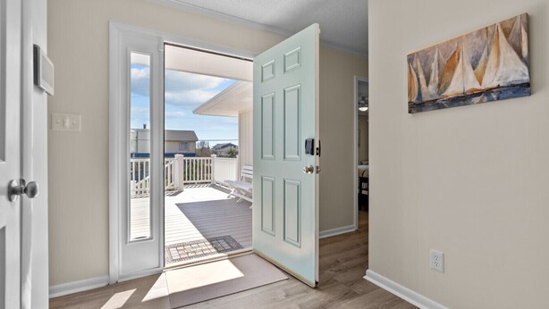 Un pasillo con una puerta que da a un balcón con vistas a casas.