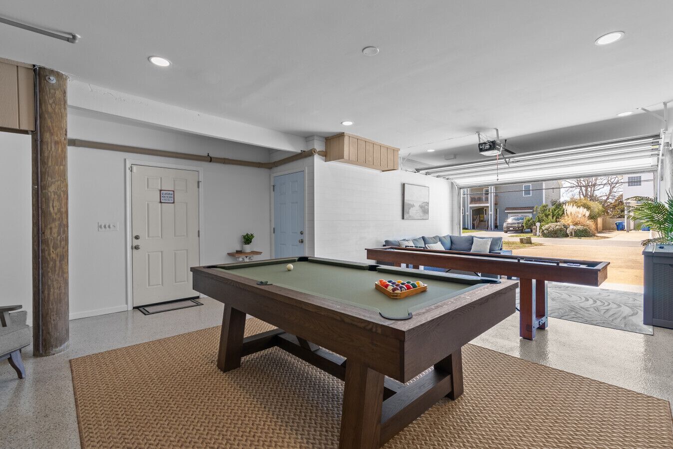 A pool table in a well-lit indoor space with a view of the outside.