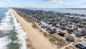 Vista aérea de una zona residencial costera con casas a lo largo de la playa y una carretera que discurre paralela a la orilla.