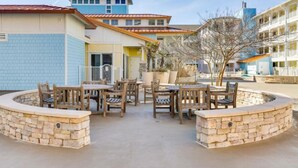 A courtyard with outdoor seating, stone walls, and buildings in the background. - New! 3Bd 2Bth Oceanfront / Pool / Gym / Beach (Virginia Beach)