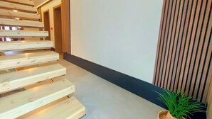 Een modern interieur met een houten trap, een aan de muur bevestigd scherm en een potplant.