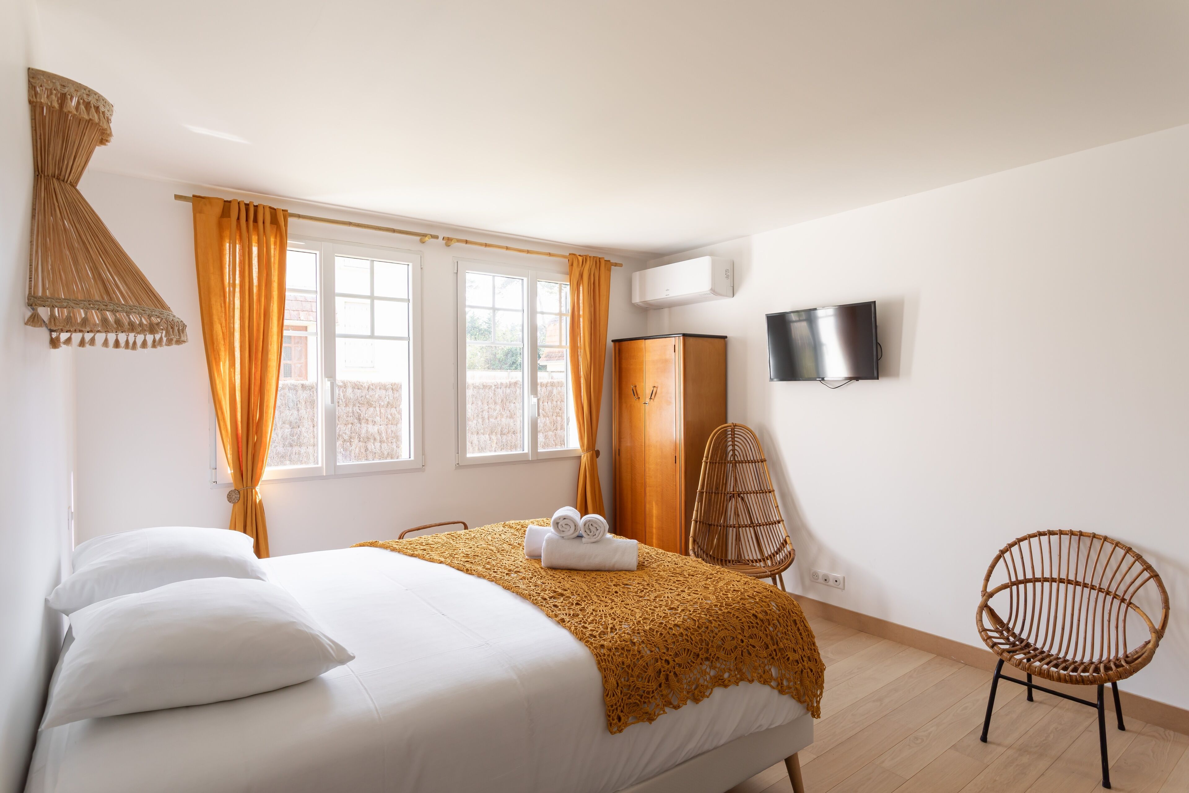 Un dormitorio con una cama, dos sillas, un televisor y un armario.