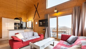 Ein modernes Blockhaus-Interieur mit Küche, Essbereich und großem Fenster mit Blick auf ein Gebäude.