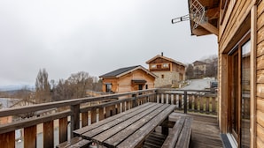 Eine Holzterrasse mit Picknicktischen mit Blick auf eine Berglandschaft.