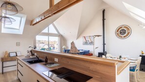 A modern kitchen with a wooden island, built-in appliances, and a large window offering a view of the outdoors. - L'Abri Côtier d'Argäe - Terrasse vue mer (Erquy)