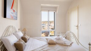 A bedroom with a bed, pillows, a window, and a painting. - L'Abri Côtier d'Argäe - Terrasse vue mer (Erquy)