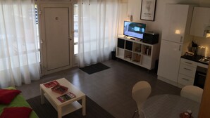 A compact living space with a TV, a small dining table, a sofa, and a kitchenette. - Three semi-detached houses downtown Grenoble (Grenoble)