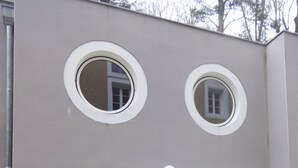 A modern building with two circular windows, a white door, and large windows with curtains. - Three semi-detached houses downtown Grenoble (Grenoble)