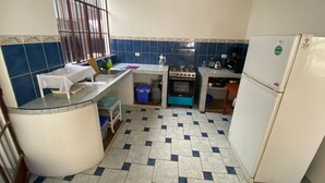 Een praktische keuken met een gasfornuis, oven, gootsteen en een koelkast.
