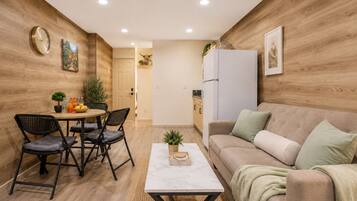 A compact living space with a dining area, a sofa, a coffee table, and a kitchen area.